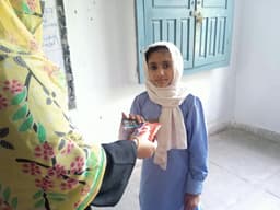 Meerab distributing packages to young girls in her community